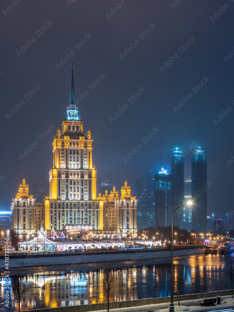 Illuminated high-rise stalinist building near river at winter night in Moscow, Russia. Historic name is Hotel Ukraine. Illuminated high-rise stalinist building near river at winter night in Moscow, Russia. Historic name is Hotel Ukraine.