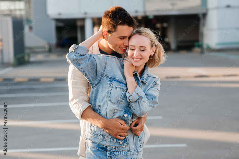 summer holidays, love and people concept - happy young couple hugging on city parking