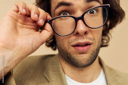 Cheerful man with glasses emotions gesture hands posing beige background