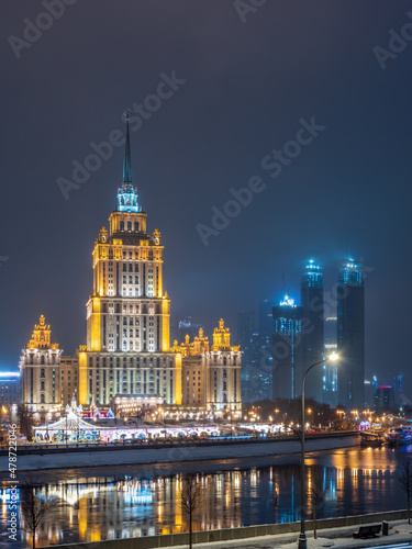 Illuminated high-rise stalinist building near river at winter night in Moscow  Russia. Historic name is Hotel Ukraine.