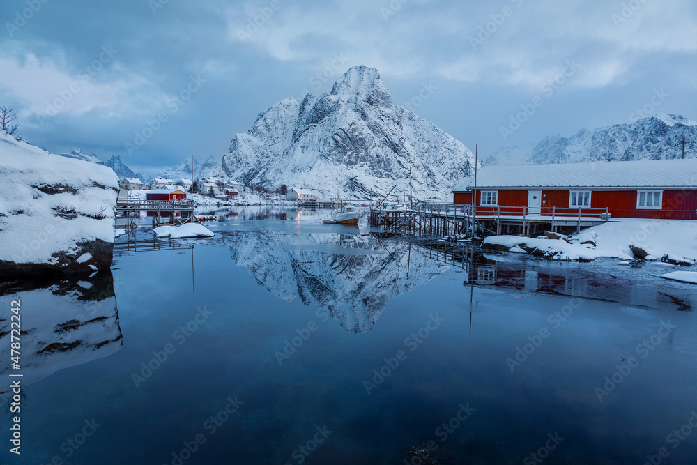 Fabulous view of the northern village. Snow-white mountain is reflected in the water. Early and quiet morning in the Norwegian harbor. The beauty of winter nature concept. Lofoten. Scandinavia. Norway
