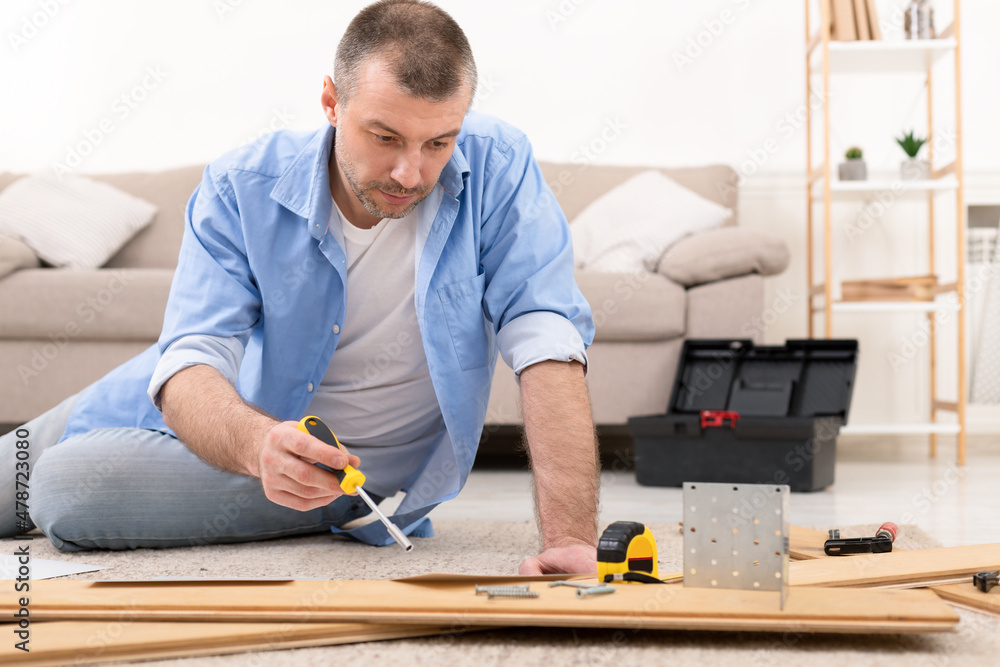 Man Fixing Wooden Cabinet Using Screwdriver And Carpentry Tools Indoor Man Fixing Wooden Cabinet Using Screwdriver And Carpentry Tools Indoor