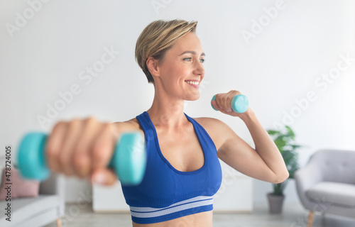 Smiling Sporty Woman Exercising With Two Dumbbells At Home