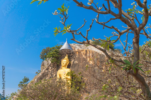 Phra Putthachai Tham Rusi Khao Ngu, golden buddha pagoda stupa, Ratchaburi, Thailand with green mountain hills and forest trees. Thai buddhist temple architecture. Tourist attraction. photo