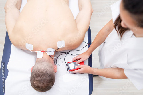 Physical therapist operating electrodes on athlete's neck photo