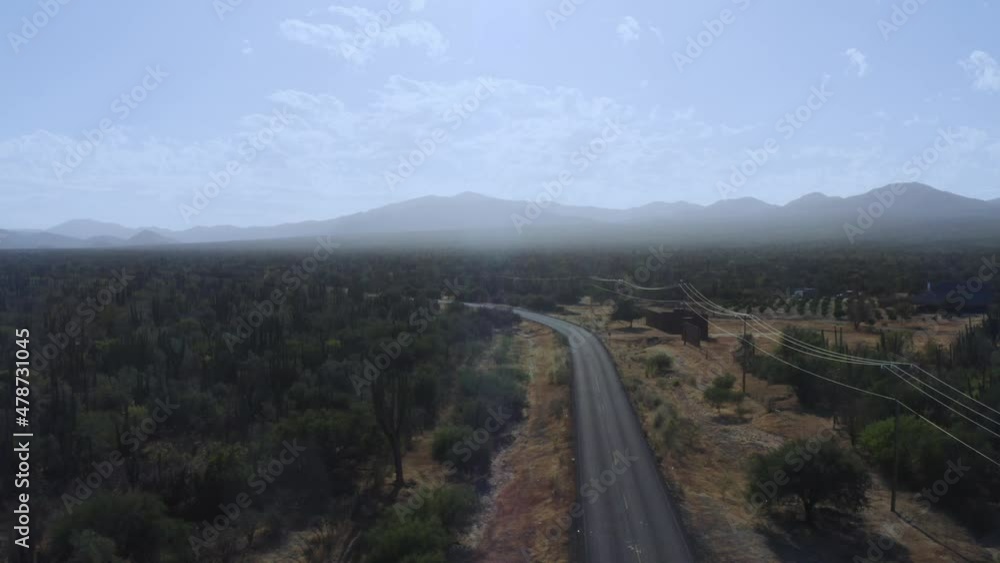 Drone shot flying over a desert road with a mountain backdrop in Mexico Drone shot flying over a desert road with a mountain backdrop in Mexico