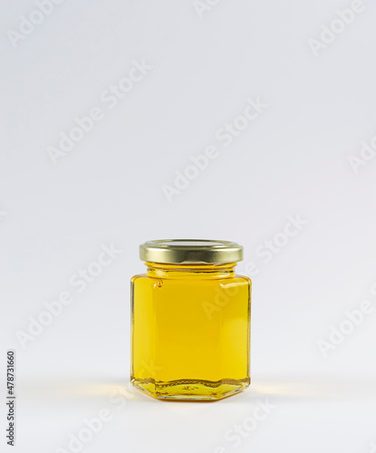 A glass jar with honey on a white background. Transparent golden nectar. Isolate on a white background. There is a place for text at the top