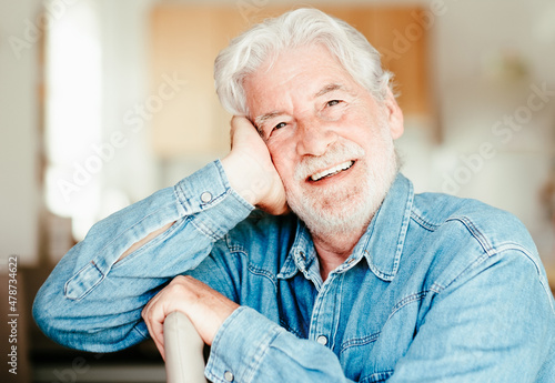 Portrait of beautiful senior bearded man smiling sitting at home looking at camera