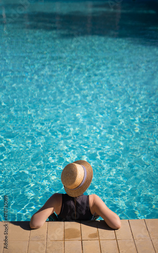 Young asian woman in hat relaxing in swimming pool spa resort, top view. vacation and relaxation concept