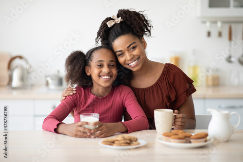 Loving black mother and daughter enjoying fresh cookies