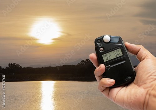 Photographers use light meters to measure correct exposure settings in landscapes at sunset.