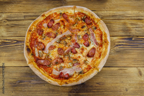 Delicious fresh pizza with sausage, mushrooms and cheese on a wooden table. Top view
