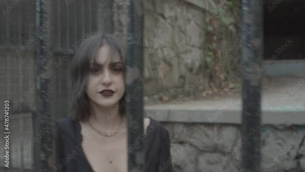 Slow motion clip of a gothic girl model smiling behind bars imprisoned in a jail Slow motion clip of a gothic girl model smiling behind bars imprisoned in a jail