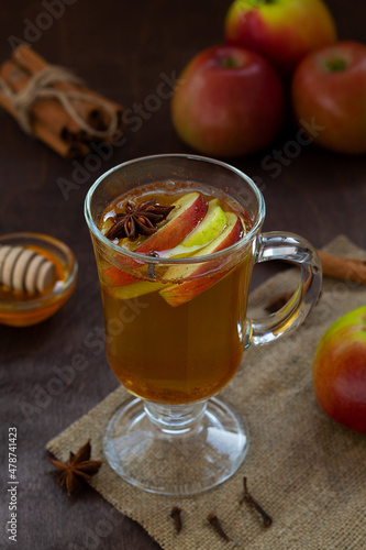 apple cider with fresh apples and honey. Hot fruit tea with spices: cinnamon, cardamon, anise, clove on the wooden table. Christmas drinks with sackcloth. mulled wine. vertical