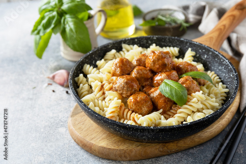 Italian  kitchen. Italian fusilli pasta with meat balls in tomato sauce and basil on grey stone background. Copy space.