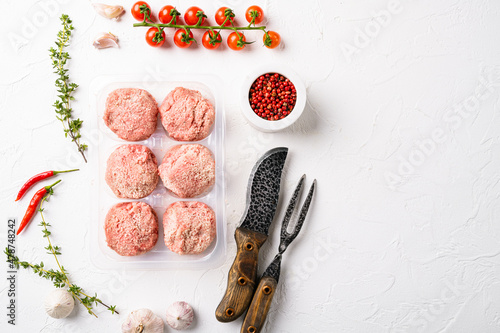 The patties of minced meat on a tray, on white stone table background, top view flat lay, with copy space for text