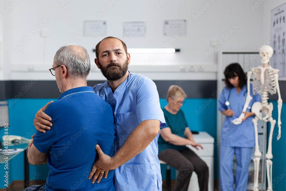 Obraz premium Chiropractor treating spinal injury and back pain of old man for physiotherapy. Assistant helping aged patient with injury to recover, giving chiropractic massage for rehabilitation