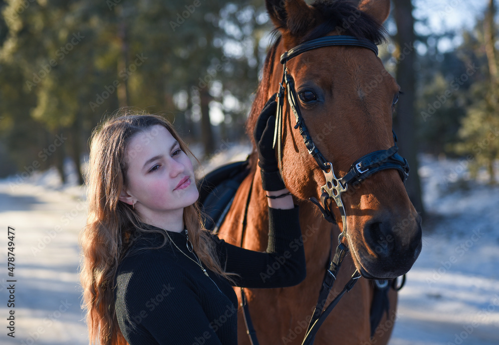 Obraz premium Young girl with horse on winter forest road