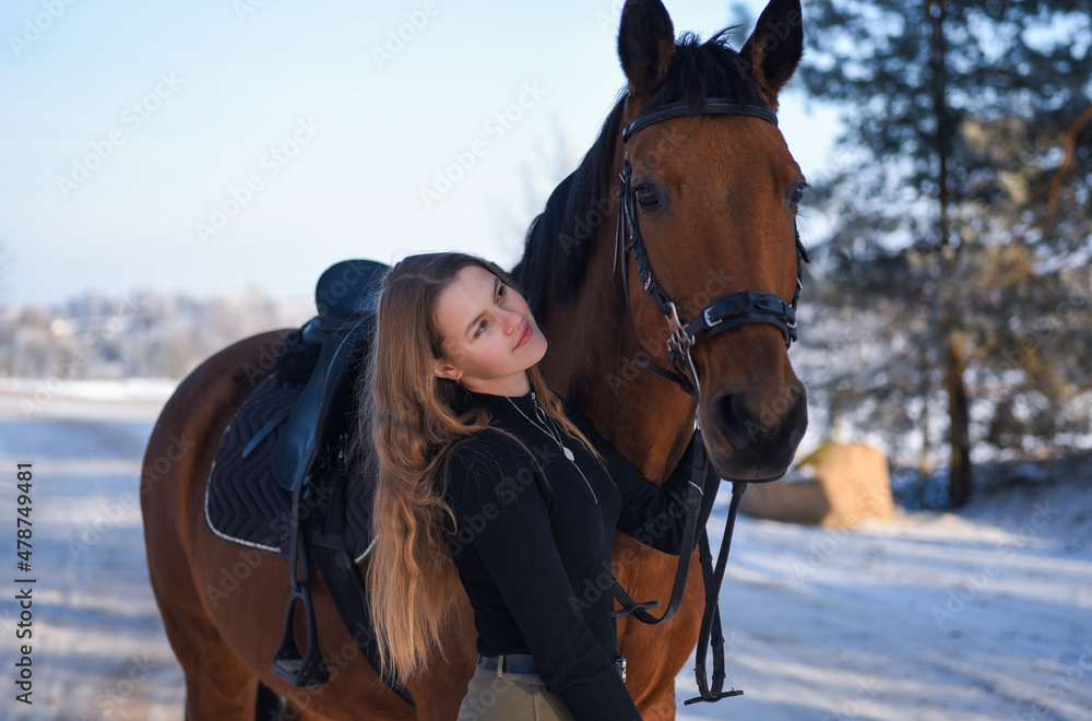 Obraz premium Young girl with horse on winter forest road