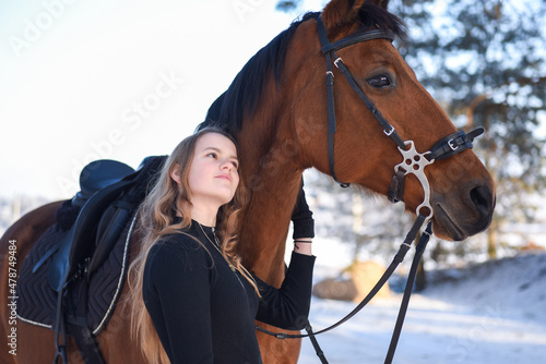 Young girl with horse on winter forest road