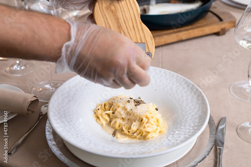 grana padana cheese pasta with truffles. chef is cooking spaghetti in parmesan head. selective focus photo