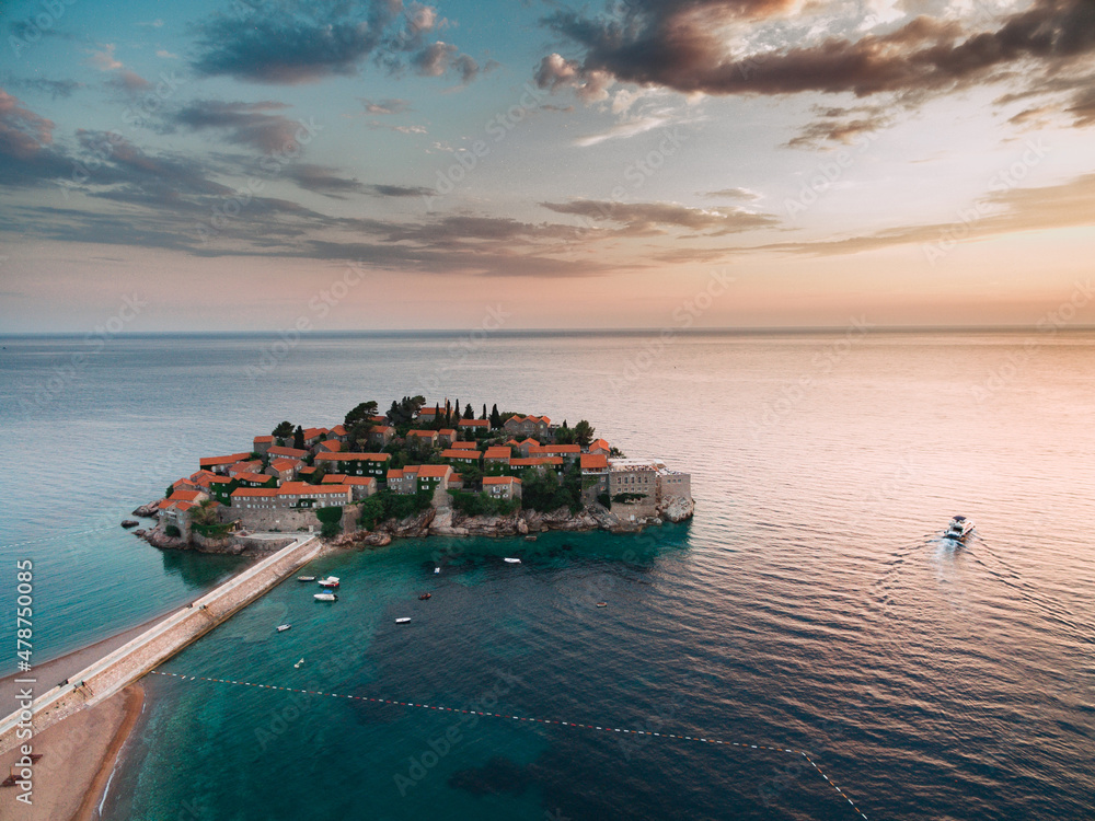 Sveti Stefan Island in the light of the pink sunset rays of the sun. Montenegro