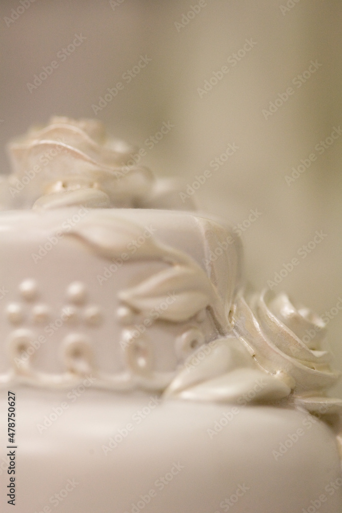 White rose wedding cake decoration on unfocused white background. Full frame, selective focus, extreme close-up. 