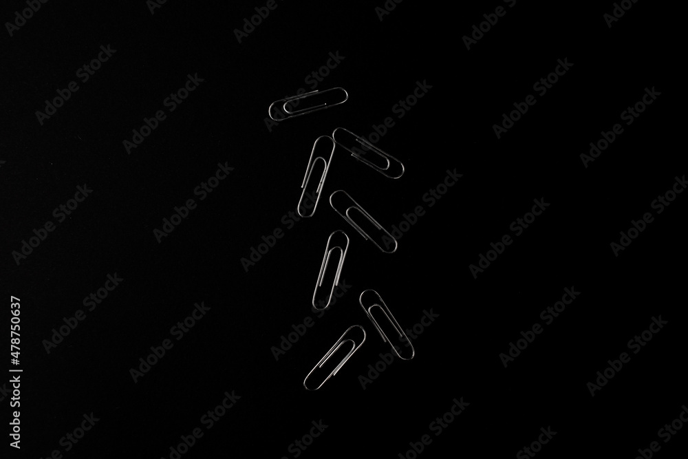 Metal paper clips lie on a black background Metal paper clips lie on a black background