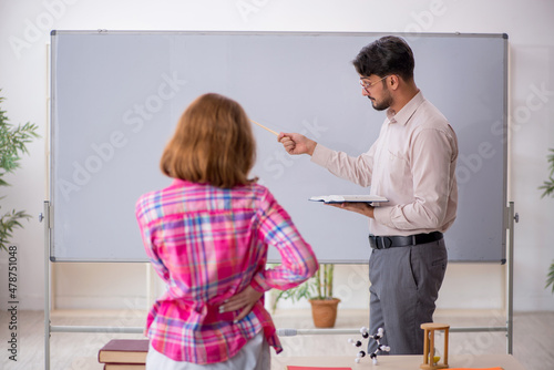 Young male teacher and redhead girl in the classroom