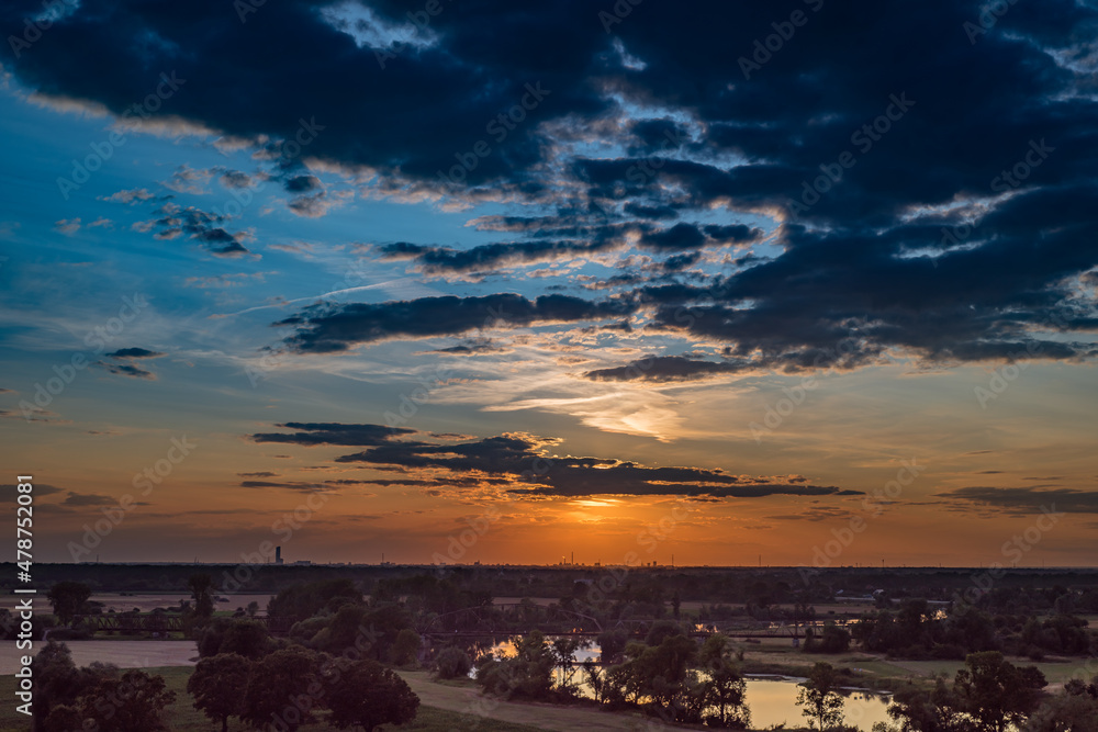 Rural landscape with river and city on the horizon, at sunset.