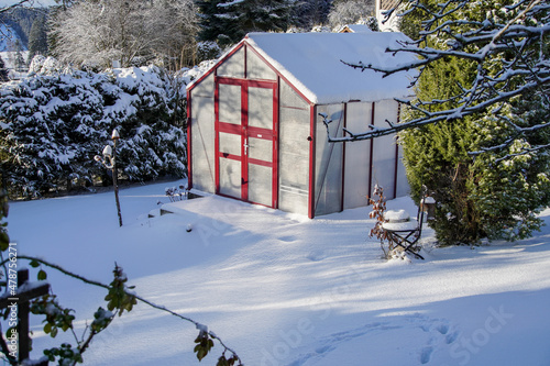 Ein Gewächshaus im Winter mit viel Schnee im Garte Eigenheim