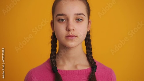 Cheerful girl with pigtails opening her eyes at the camera in the yellow studio