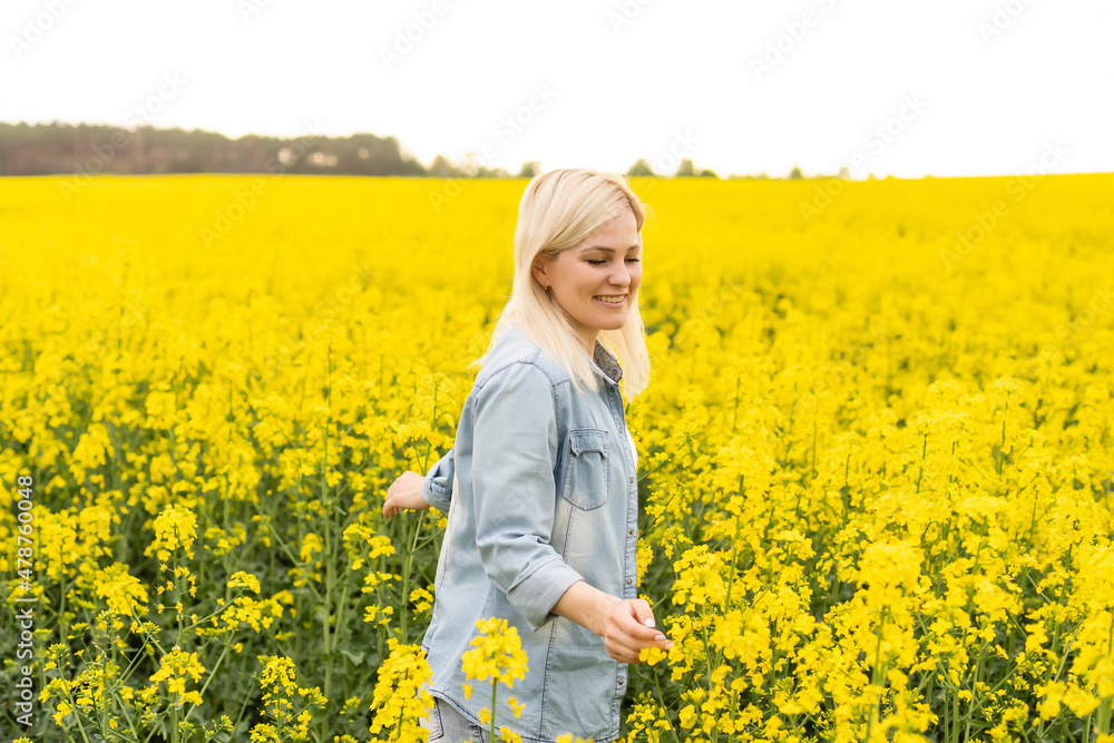 Portrait of attractive woman on blooming rapeseed field with sunset light. Yellow flowers and happy woman Portrait of attractive woman on blooming rapeseed field with sunset light. Yellow flowers and happy woman
