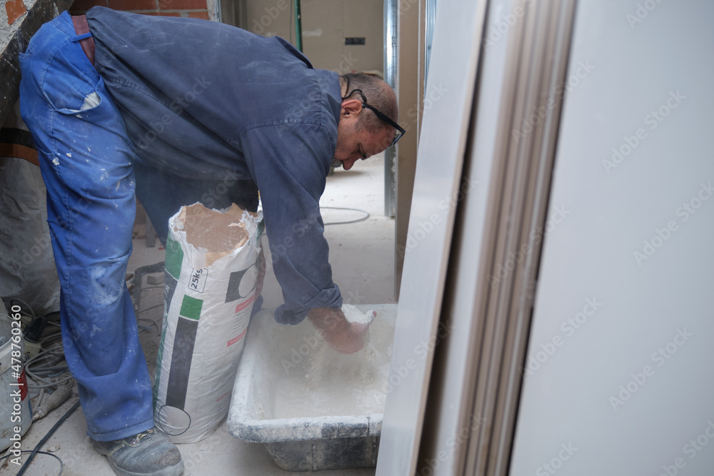 Senior constructor worker preparing tile adhesive mortar. Senior constructor worker preparing tile adhesive mortar.
