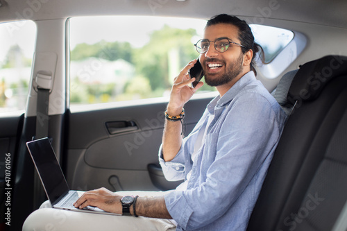 Positive indian man freelancer working online while sitting in taxi © Prostock-studio