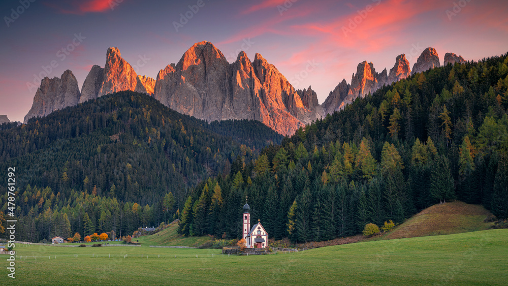 Autumn in Alps. Panoramic image of magical Dolomites mountains in a gorgeous Val di Funes valley, South Tyrol, Italian Alps at autumn sunset.
