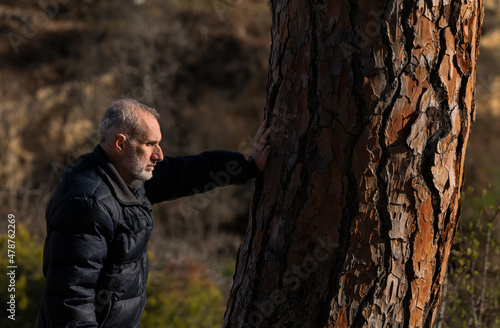 Portrait of adult man against tree trunk