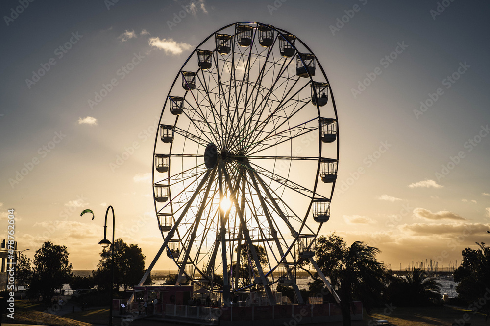 Ferris Wheel on the Beach at Sunset with Golden Sun Rays