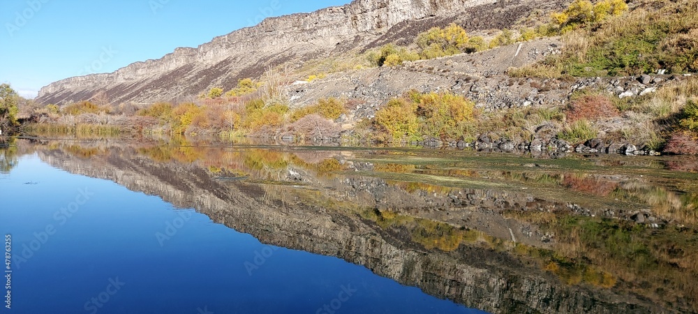 Reflection of the shore in the clear blue water of the river. Autumn, vacation, fishing. Silence
