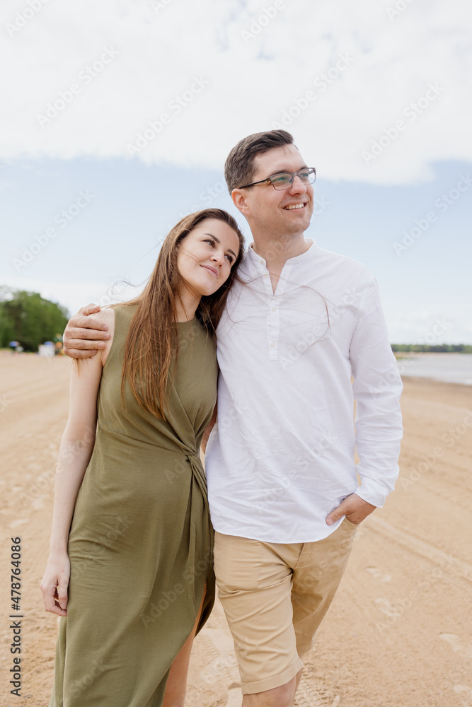 Obraz premium a couple of a man and a woman are walking on the beach or running along the sand along the seashore. beautiful and young European man and woman on a romantic walk in nature, a couple in love, a happy