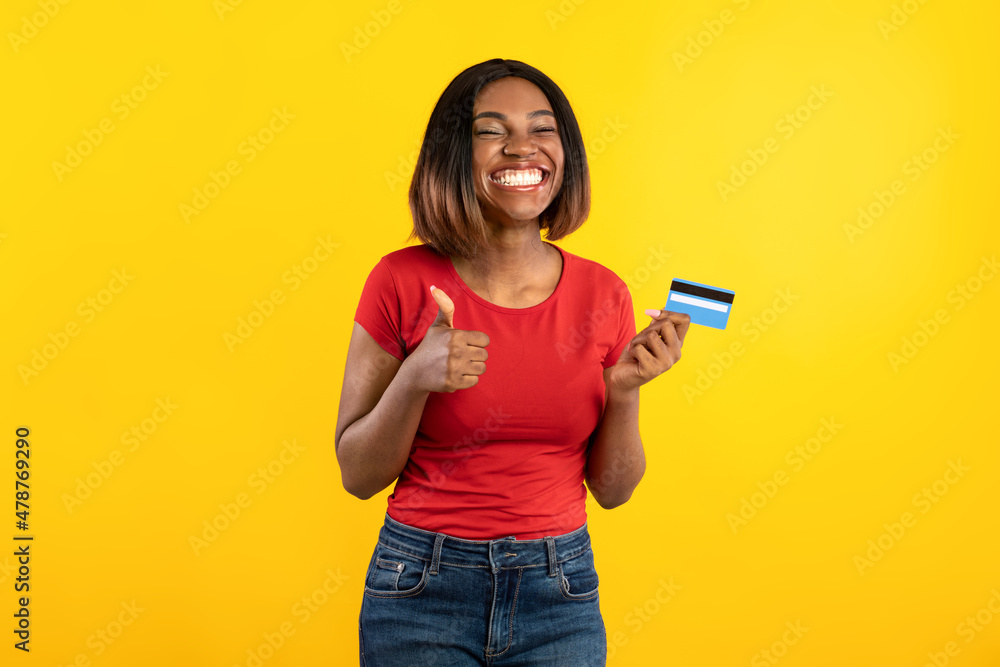 Cheerful Black Female Showing Credit Card And Like, Yellow Background Cheerful Black Female Showing Credit Card And Like, Yellow Background