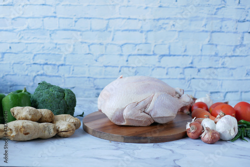  raw whole chicken and vegetables on tiles background  photo