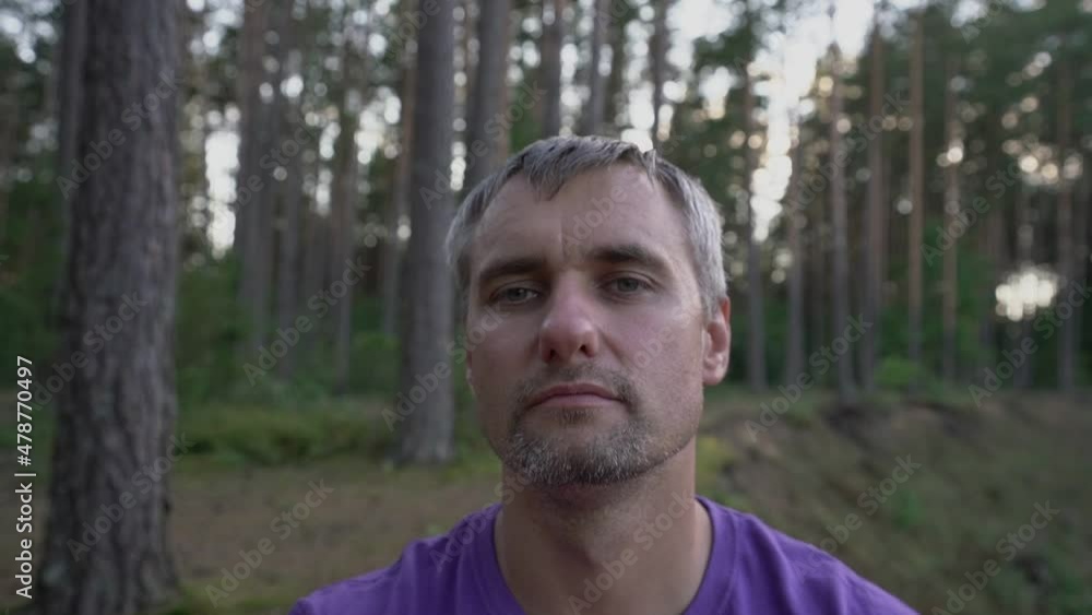adult relaxed man in forest in nature meditates with closed eyes opening them and closing them closeup adult relaxed man in forest in nature meditates with closed eyes opening them and closing them closeup