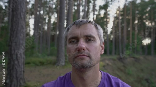 adult relaxed man in forest in nature meditates with closed eyes opening them and closing them closeup photo