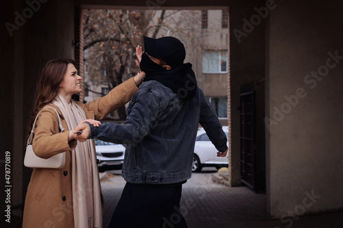 Woman defending herself from attacker with knife in alley photo