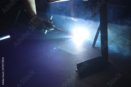 Skillful metal worker working with arc welding machine in factory while wearing safety equipment. Metalwork manufacturing and construction maintenance service by manual skill labor concept.