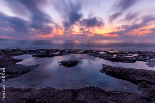 Twilight scenic sea landscape with beautiful shore, blurred flying dramatic blue clouds, amazing shoreline and sunset on background