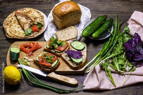 Sandwiches with salmon and greens. Sandwich with cottage cheese and basil and cucumber. Dark background.