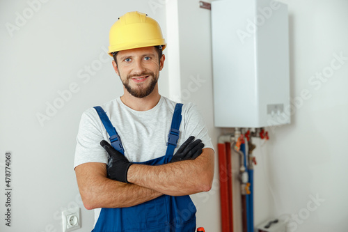 Fotografie Cheerful male worker, technician servicing the house heating system smiling at c