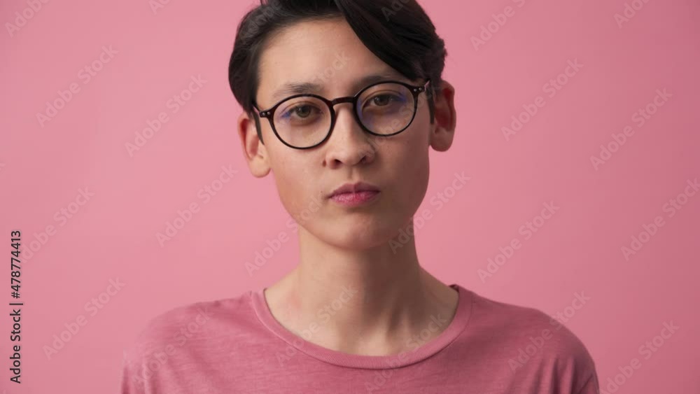 Concentrated Asian man putting on eyeglasses in the pink studio Concentrated Asian man putting on eyeglasses in the pink studio